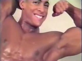 Young bodybuilder oiling up for posing