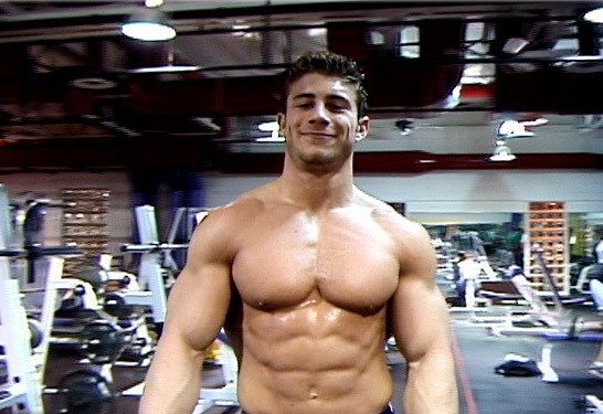 Nate Morton smiling while showing off his pumped-up body during a workout.