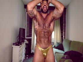 Muscle poses in skimpy gold trunks